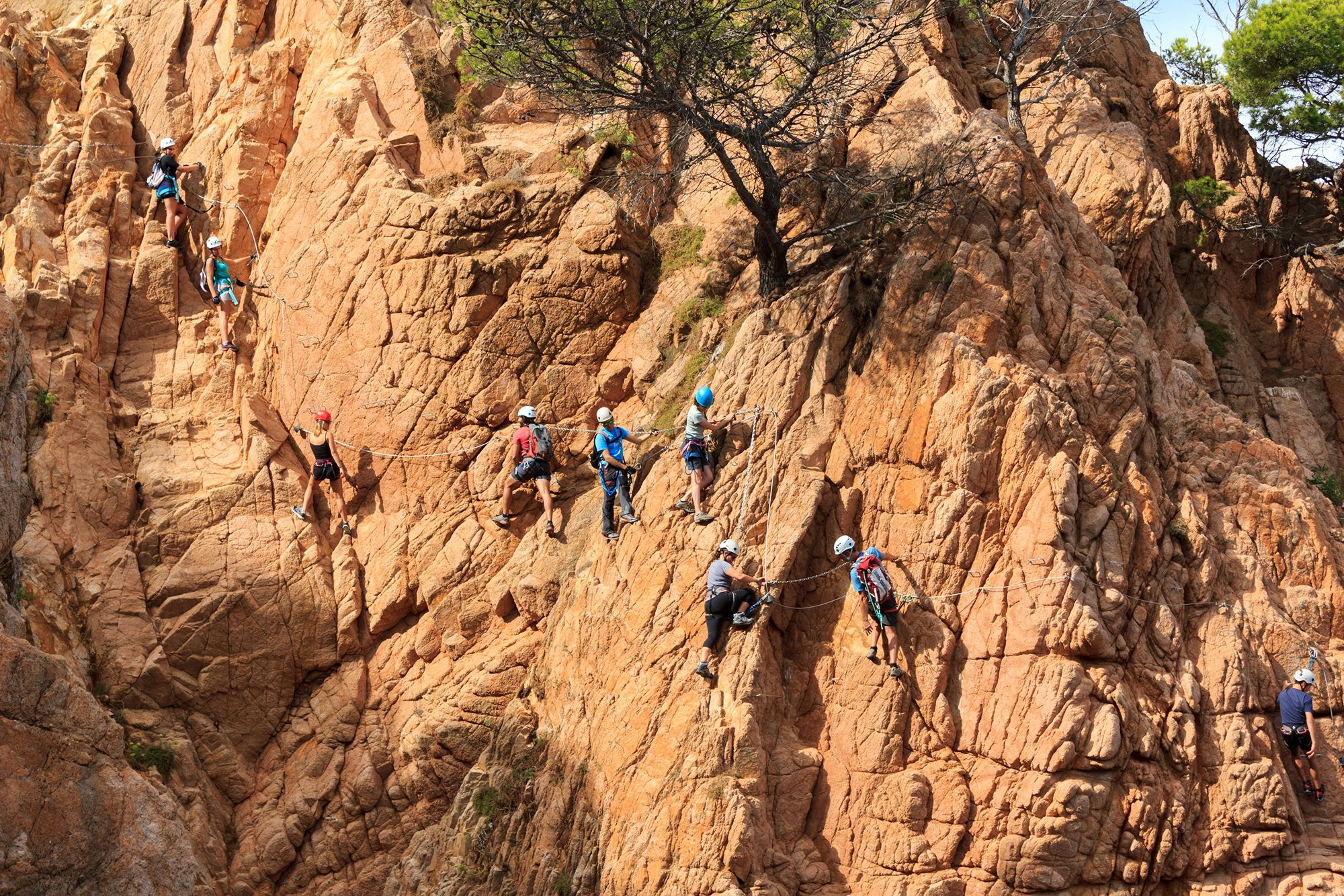 Equipo de escaladores ligados por una cuerda ascendiendo por una ladera rocosa